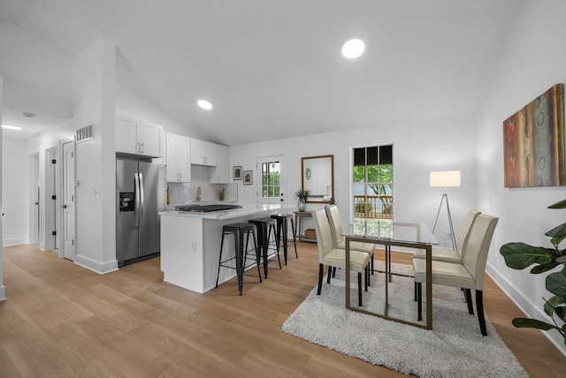 1047 Cherry Bud Dr, Columbus, OH 43228 - kitchen featuring stainless steel fridge, vaulted ceiling, a kitchen bar, white cabinetry, and a center island