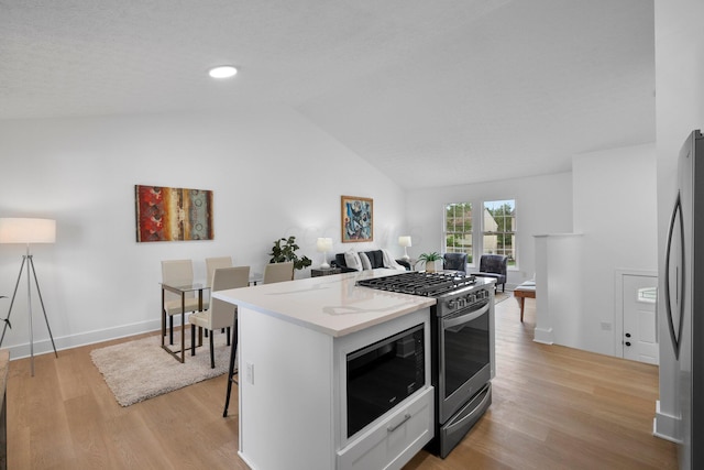 1047 Cherry Bud Dr, Columbus, OH 43228 - kitchen featuring appliances with stainless steel finishes, vaulted ceiling, light wood finished floors, open floor plan, and a kitchen island
