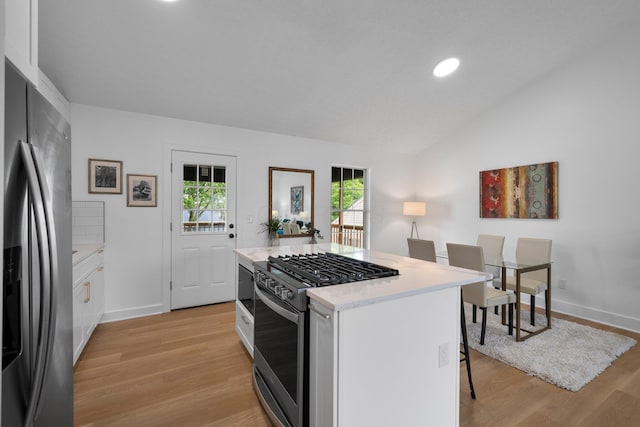 1047 Cherry Bud Dr, Columbus, OH 43228 - kitchen featuring appliances with stainless steel finishes, vaulted ceiling, light wood-style flooring, light countertops, and a kitchen breakfast bar