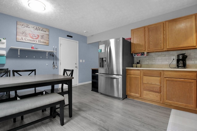 4037 Millview Ct, Columbus, OH 43207 - kitchen with stainless steel fridge, a textured ceiling, decorative backsplash, light countertops, and light wood-style floors