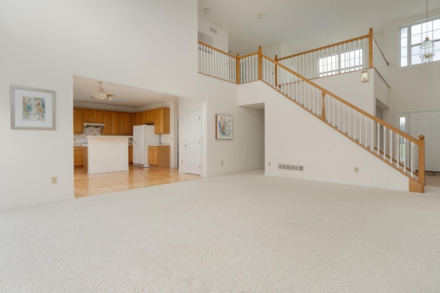 3899 Hampshire Ave, Powell, OH 43065 - unfurnished living room featuring a high ceiling, light carpet, and stairs