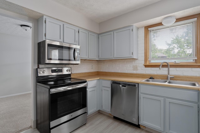 3456 Merrydawn Dr, Columbus, OH 43221 - kitchen featuring stainless steel appliances, a sink, a textured ceiling, light countertops, and decorative backsplash