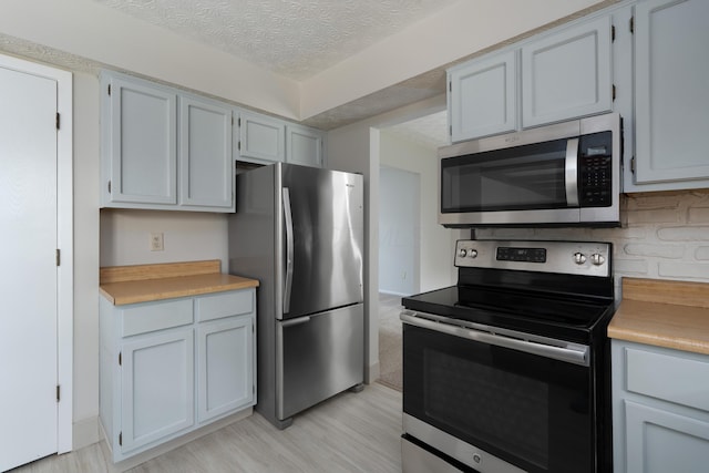 3456 Merrydawn Dr, Columbus, OH 43221 - kitchen with stainless steel appliances, light countertops, light wood-style flooring, and a textured ceiling