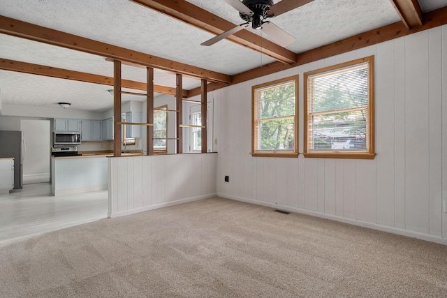 3456 Merrydawn Dr, Columbus, OH 43221 - unfurnished living room with beamed ceiling, light colored carpet, ceiling fan, a textured ceiling, and baseboards