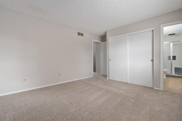3456 Merrydawn Dr, Columbus, OH 43221 - unfurnished bedroom featuring light carpet, a closet, connected bathroom, a textured ceiling, and a fireplace