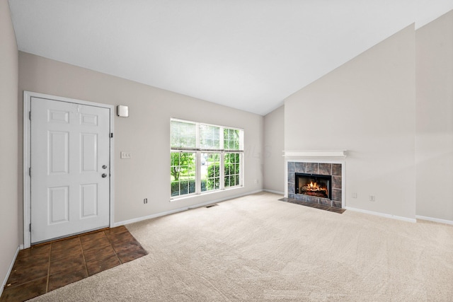 857 Village Dr, Delaware, OH 43015 - unfurnished living room featuring carpet floors, a tiled fireplace, baseboards, and vaulted ceiling