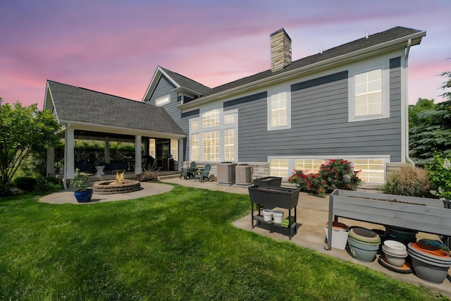 5781 Glendavon Loop, Dublin, OH 43016 - back of property at dusk featuring an outdoor fire pit, a patio area, a chimney, and a yard