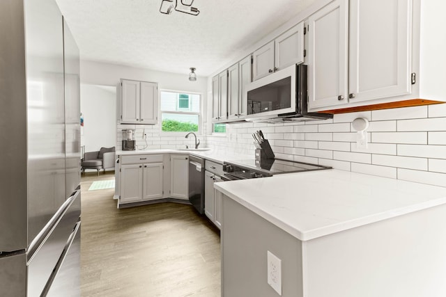 4465 Big Walnutview Dr, Columbus, OH 43230 - kitchen with stainless steel appliances, light wood-style flooring, decorative backsplash, a sink, and a textured ceiling