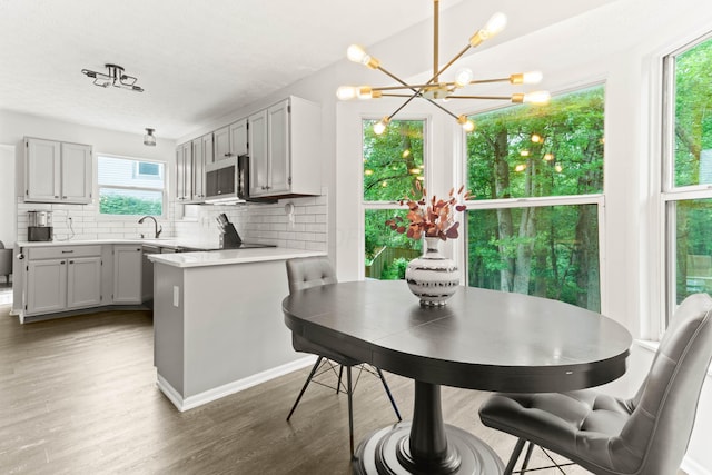 4465 Big Walnutview Dr, Columbus, OH 43230 - kitchen with tasteful backsplash, a peninsula, stainless steel microwave, a chandelier, and wood finished floors