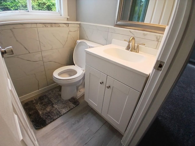 2489 Lipton Rd, Columbus, OH 43232 - half bathroom with tile walls, vanity, toilet, wood finished floors, and wainscoting