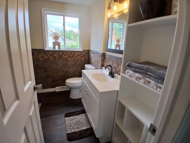 2489 Lipton Rd, Columbus, OH 43232 - bathroom with tile walls, toilet, vanity, plenty of natural light, and a wainscoted wall