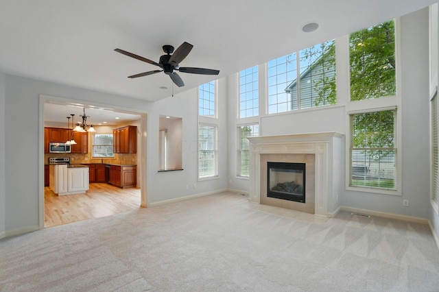 273 Blue Jacket Cir, Pickerington, OH 43147 - unfurnished living room featuring light carpet, baseboards, a fireplace, ceiling fan, and a chandelier