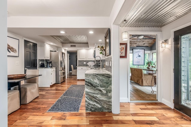 8547 Pitlochry Ct, Dublin, OH 43017 - kitchen featuring stainless steel fridge, light wood finished floors, white cabinetry, decorative backsplash, and a sink