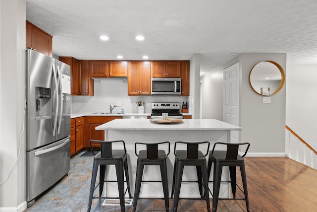 4373 Valley Quail Blvd S, Westerville, OH 43081 - kitchen featuring appliances with stainless steel finishes, a sink, a kitchen bar, backsplash, and a kitchen island