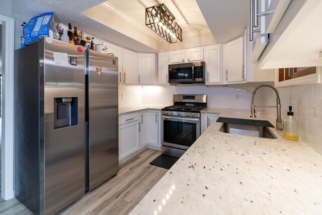 3243 Brookview Way Unit 68, Columbus, OH 43221 - kitchen featuring appliances with stainless steel finishes, a sink, light stone counters, light wood-type flooring, and white cabinets