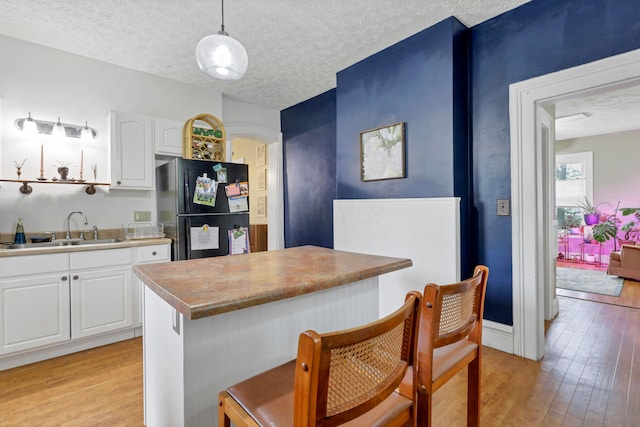 1904 Cedar Hill Rd, Lancaster, OH 43130 - kitchen with freestanding refrigerator, light wood-style flooring, a sink, a kitchen bar, and white cabinets