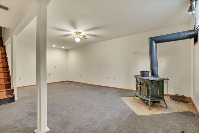 907 Fairfield Ave, Lancaster, OH 43130 - unfurnished living room with a wood stove, stairs, ceiling fan, carpet flooring, and baseboards
