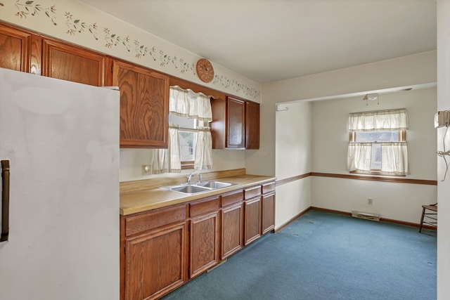 907 Fairfield Ave, Lancaster, OH 43130 - kitchen featuring a sink, freestanding refrigerator, light countertops, carpet floors, and brown cabinetry