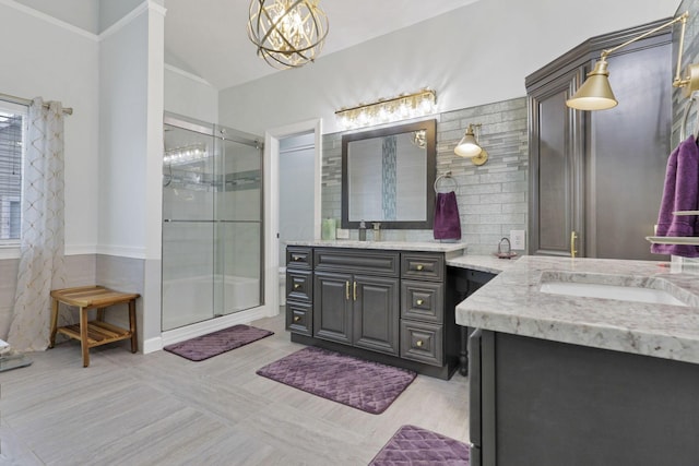 217 Warbler Ct, Pickerington, OH 43147 - bathroom featuring two vanities, a stall shower, lofted ceiling, backsplash, and a chandelier