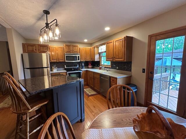 14629 Hock Hocking Rd, Logan, OH 43138 - kitchen with appliances with stainless steel finishes, light wood-style floors, a sink, backsplash, and pendant lighting