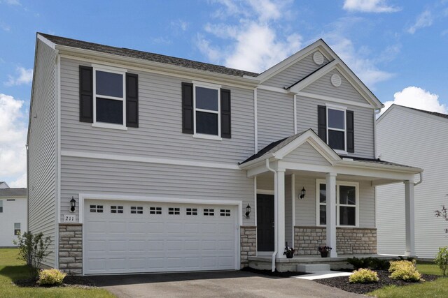 211 Whitetail Trl, Johnstown, OH 43031 - view of front of home with a porch, stone siding, a garage, and asphalt driveway