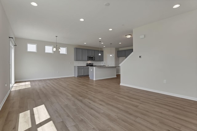 211 Whitetail Trl, Johnstown, OH 43031 - unfurnished living room featuring light wood-type flooring, recessed lighting, a chandelier, and baseboards