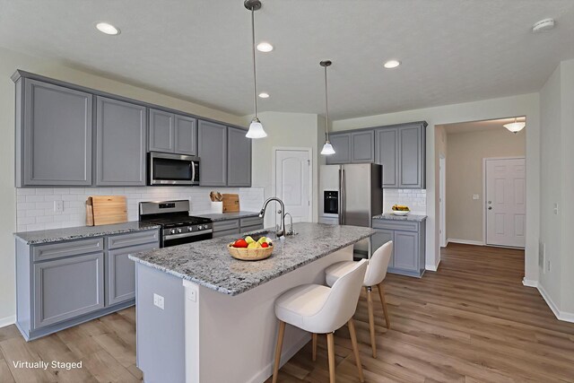 211 Whitetail Trl, Johnstown, OH 43031 - kitchen with appliances with stainless steel finishes, gray cabinetry, tasteful backsplash, a sink, and light wood finished floors