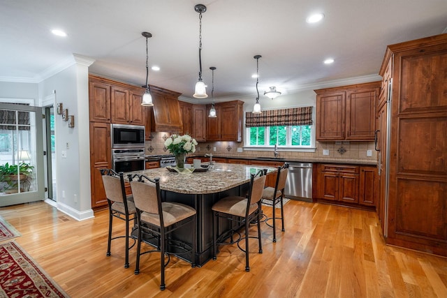 7699 Clear Creek Ct, Blacklick, OH 43004 - kitchen with stainless steel appliances, ornamental molding, a kitchen breakfast bar, a center island with sink, and light wood finished floors