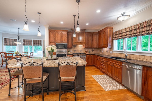7699 Clear Creek Ct, Blacklick, OH 43004 - kitchen with stainless steel appliances, a sink, light stone countertops, crown molding, and brown cabinetry