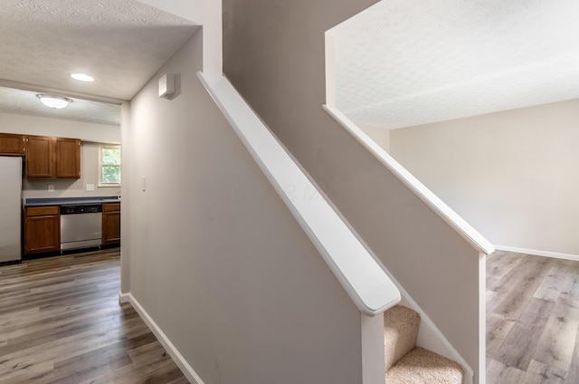 3248 Medoma Dr, Columbus, OH 43204 - stairs featuring wood finished floors, a textured ceiling, and recessed lighting