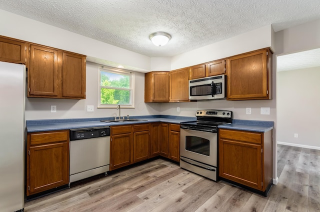 3248 Medoma Dr, Columbus, OH 43204 - kitchen featuring appliances with stainless steel finishes, light wood-style floors, dark countertops, and a textured ceiling