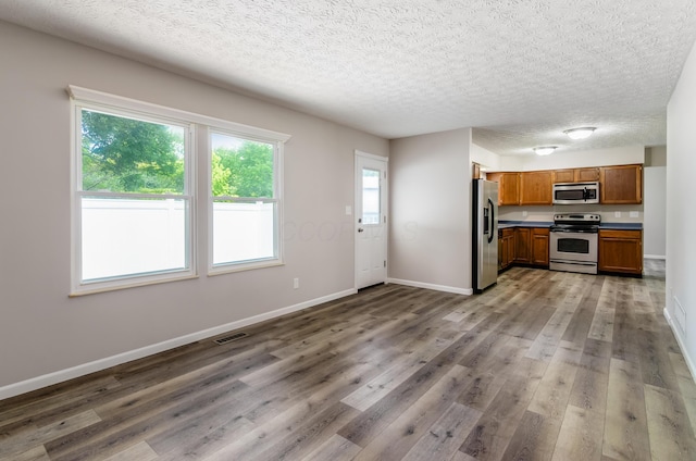 3248 Medoma Dr, Columbus, OH 43204 - kitchen with stainless steel appliances, wood finished floors, brown cabinets, a textured ceiling, and dark countertops