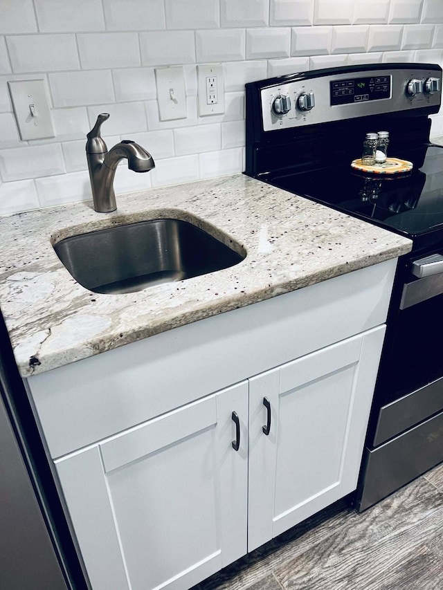 3037 La Vista Dr Unit 39, Columbus, OH 43204 - kitchen view of stainless steel electric range oven, a sink, white cabinets, tasteful backsplash, and light stone counters