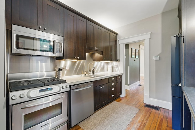 420 Stanley Ave, Columbus, OH 43206 - kitchen with stainless steel appliances, a sink, light wood finished floors, and dark brown cabinetry