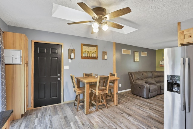 14609 Hock Hocking Rd, Logan, OH 43138 - dining area with light wood-type flooring, a ceiling fan, a textured ceiling, baseboards, and a skylight