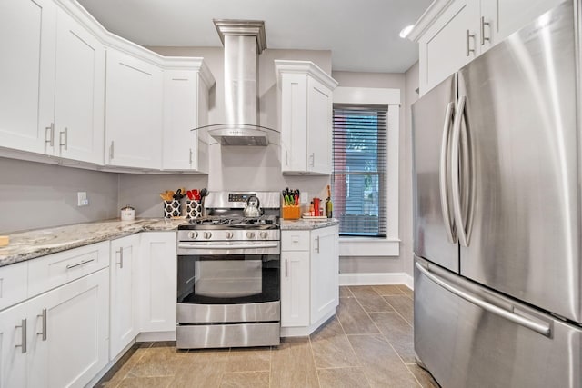 663 Wilson Ave, Columbus, OH 43205 - kitchen featuring stainless steel appliances, wall chimney exhaust hood, white cabinets, light stone counters, and baseboards