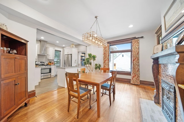 663 Wilson Ave, Columbus, OH 43205 - dining space featuring a fireplace with flush hearth, light wood-type flooring, recessed lighting, baseboards, and a chandelier