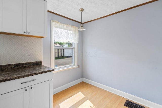 644 Eastmoor Blvd, Columbus, OH 43209 - unfurnished dining area with crown molding, light wood-type flooring, baseboards, and a textured ceiling