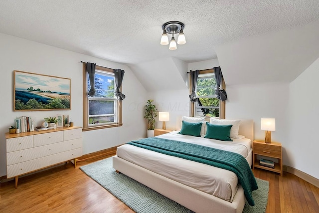 644 Eastmoor Blvd, Columbus, OH 43209 - bedroom featuring light wood-style flooring, multiple windows, vaulted ceiling, and a textured ceiling