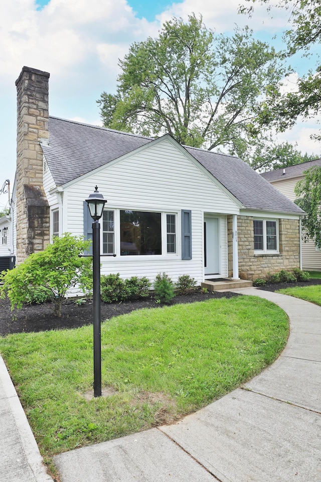 2009 Zollinger Rd, Columbus, OH 43221 - view of front of property with a shingled roof, a front yard, stone siding, and a chimney