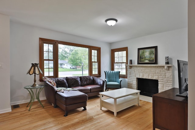 2009 Zollinger Rd, Columbus, OH 43221 - living room with a stone fireplace, light wood-style flooring, and baseboards