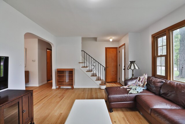 2009 Zollinger Rd, Columbus, OH 43221 - living room featuring light wood-style floors, stairs, arched walkways, and baseboards