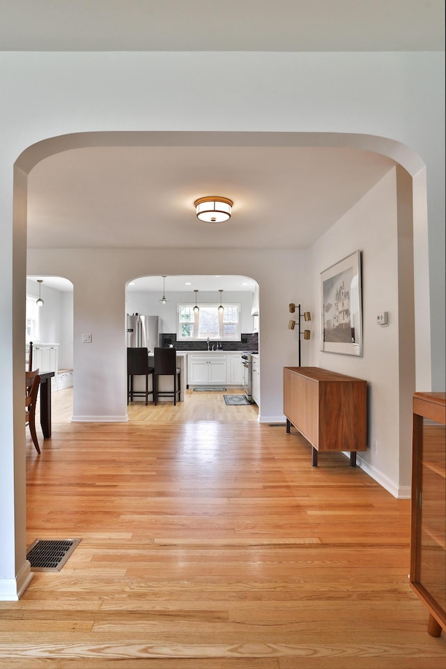 2009 Zollinger Rd, Columbus, OH 43221 - hallway featuring arched walkways, light wood-style flooring, baseboards, and a sink