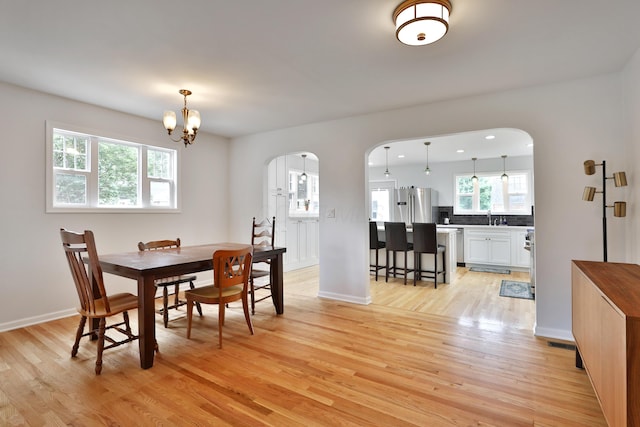 2009 Zollinger Rd, Columbus, OH 43221 - dining space with arched walkways, light wood-type flooring, a chandelier, and baseboards