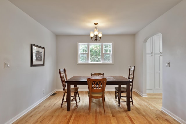2009 Zollinger Rd, Columbus, OH 43221 - dining room featuring arched walkways, light wood-type flooring, a chandelier, and baseboards
