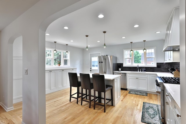 2009 Zollinger Rd, Columbus, OH 43221 - kitchen featuring appliances with stainless steel finishes, light wood-style flooring, decorative backsplash, arched walkways, and recessed lighting