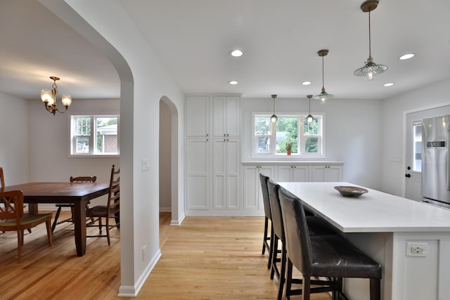 2009 Zollinger Rd, Columbus, OH 43221 - kitchen featuring arched walkways, light wood-style flooring, recessed lighting, white cabinets, and a chandelier