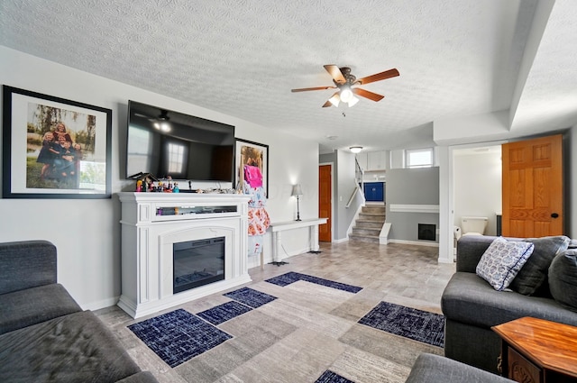 1627 Metcalfe Ave, Columbus, OH 43207 - living area featuring ceiling fan, stairway, a textured ceiling, baseboards, and a glass covered fireplace