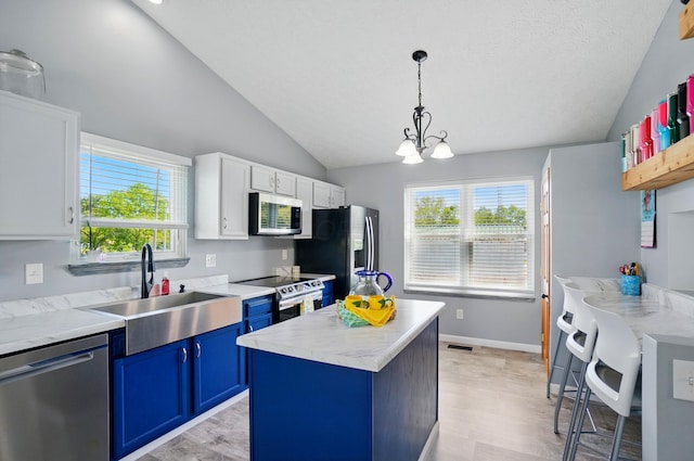 1627 Metcalfe Ave, Columbus, OH 43207 - kitchen featuring appliances with stainless steel finishes, blue cabinetry, lofted ceiling, a sink, and light wood-style floors