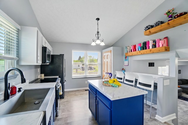 1627 Metcalfe Ave, Columbus, OH 43207 - kitchen with blue cabinets, appliances with stainless steel finishes, a sink, lofted ceiling, and baseboards